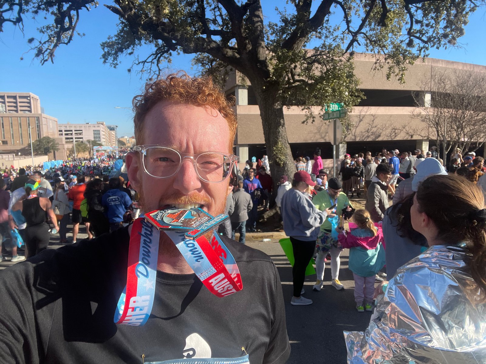 John Loughrin biting his finisher medal after the Austin Half Marathon 2023